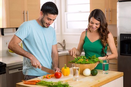 Couple happily preparing a salad together in the kitchen to represent the blog How to Succeed in the new relationship?